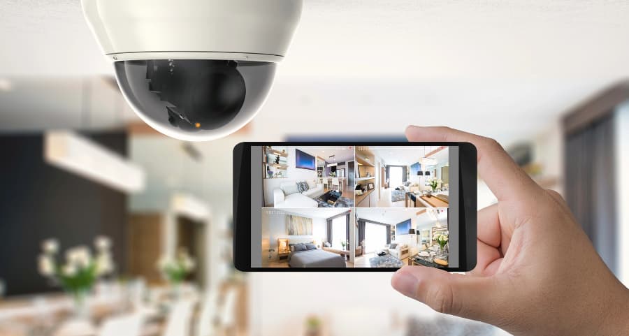 Homeowner holding smartphone with video feed from security cameras in Phoenix